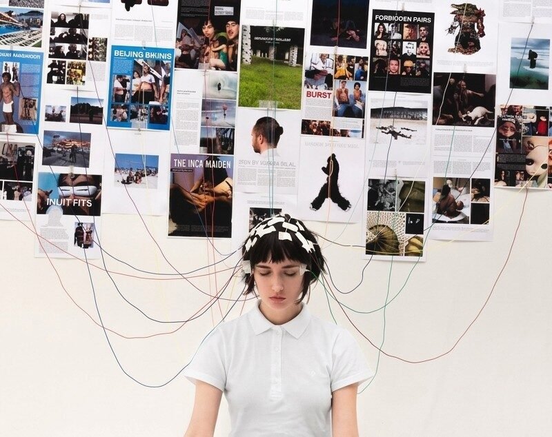 Persona con cables en su cabeza pegados a una pared con imagenes.